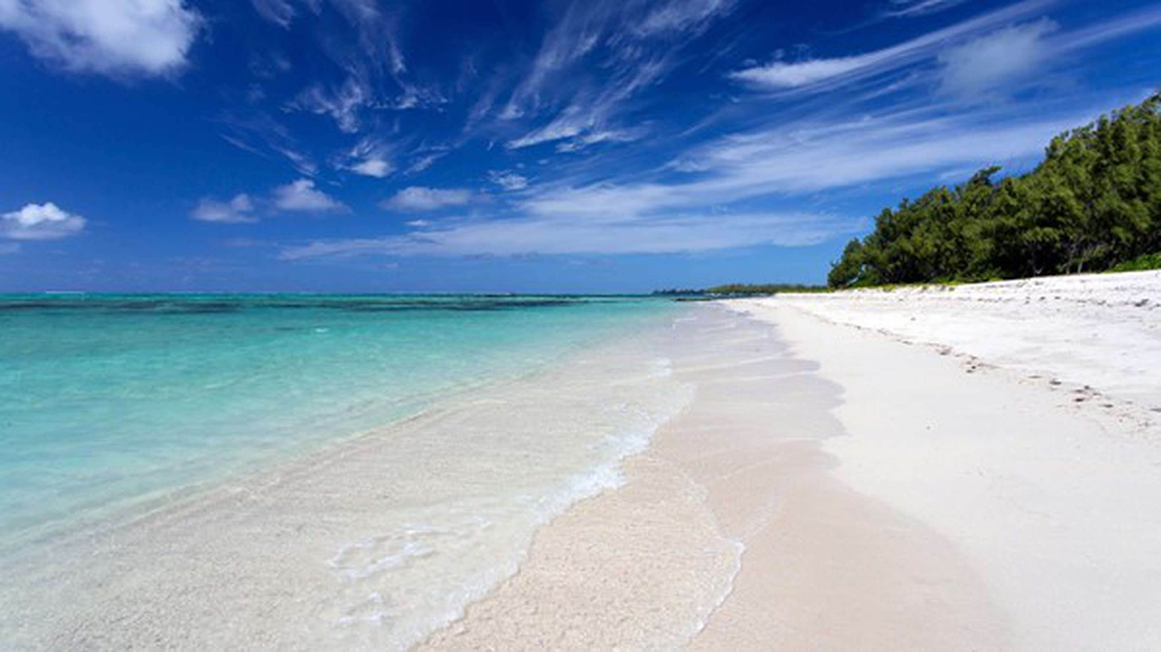 Île aux Cerfs Strand auf Mauritius. Ein schneeweisser Strand und leicht Türkisem Wasser und einem strahlend blauem Himmel mit leichten Wolken.