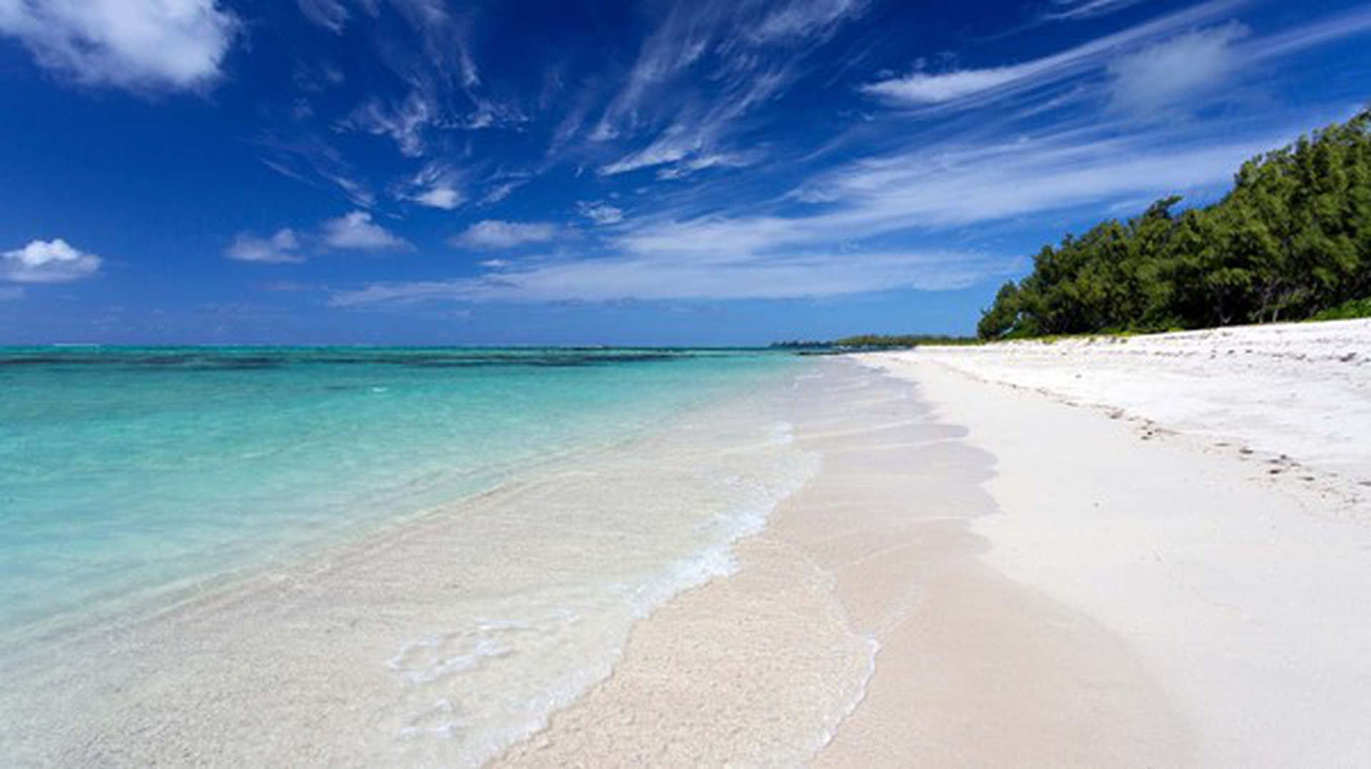 Île aux Cerfs Strand auf Mauritius. Ein schneeweisser Strand und leicht  Türkisem Wasser und einem strahlend blauem Himmel mit leichten Wolken. 