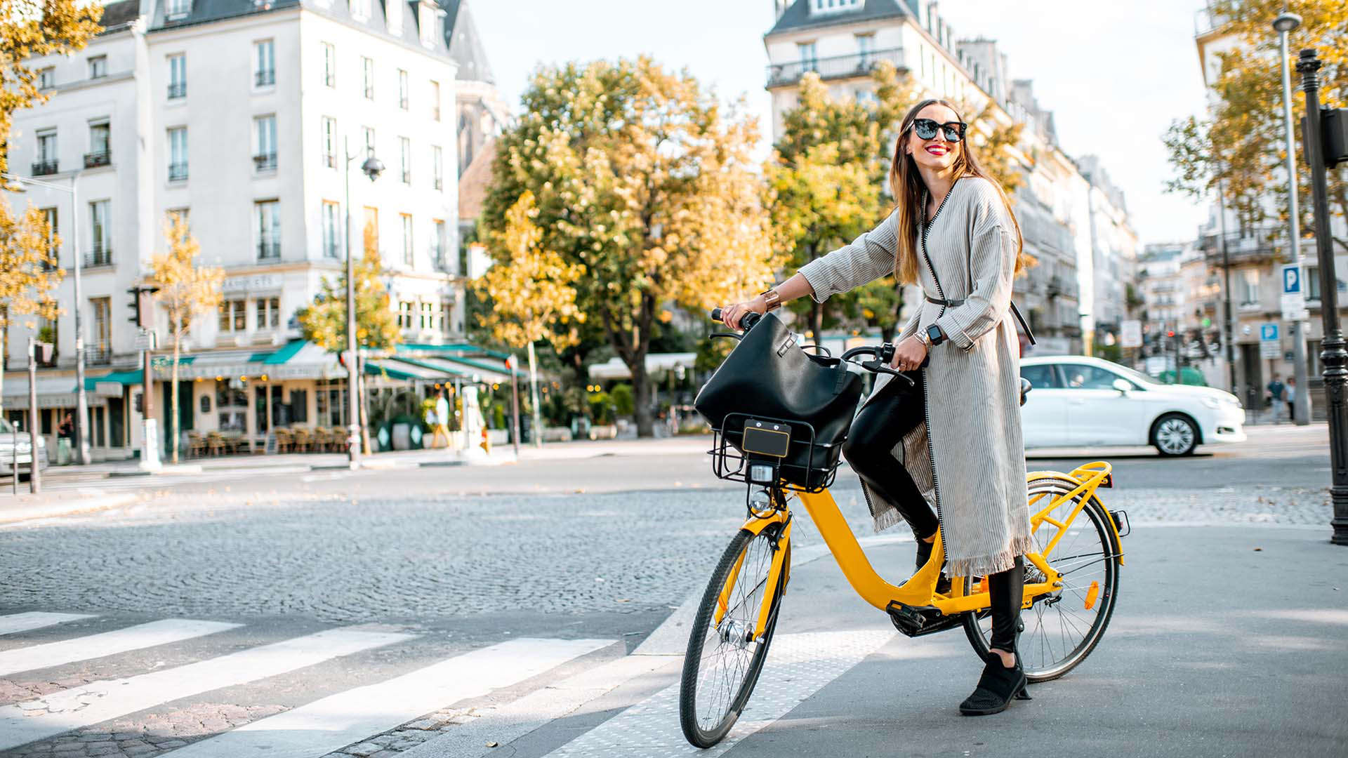 A woman wearing sunglasses cycling in Paris, France