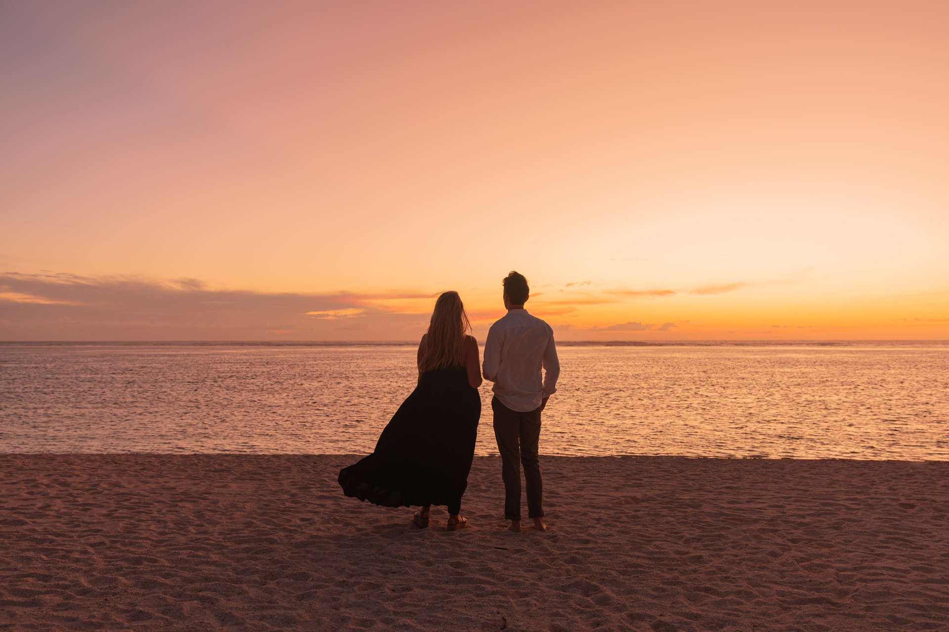 Couple watching the sunset on the beach by JW Marriott Mauritius