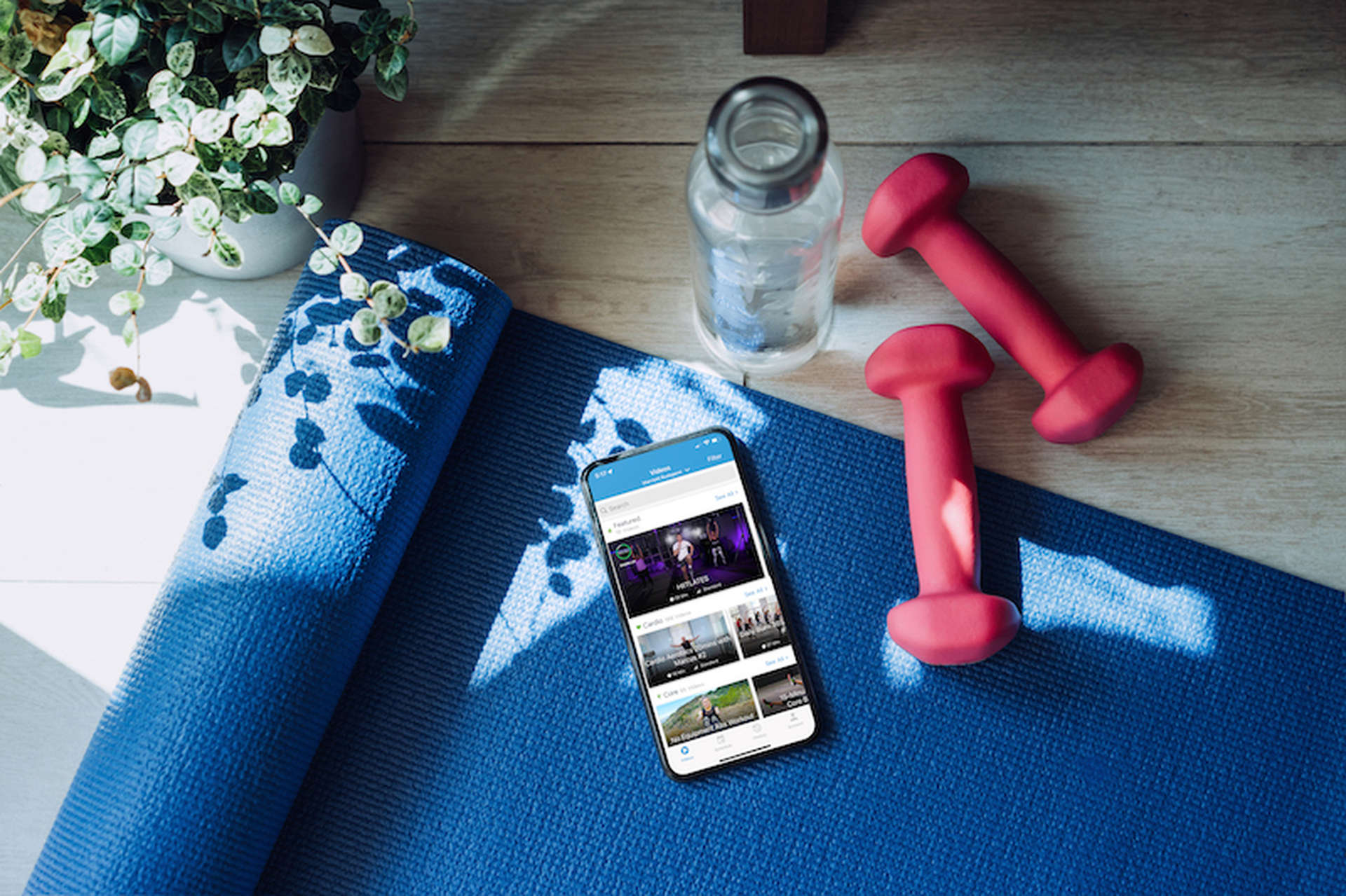 Tappetino da yoga, pesi per le mani e uno smartphone che mostra l'app Fitness On Demand di Marriott Bonvoy.