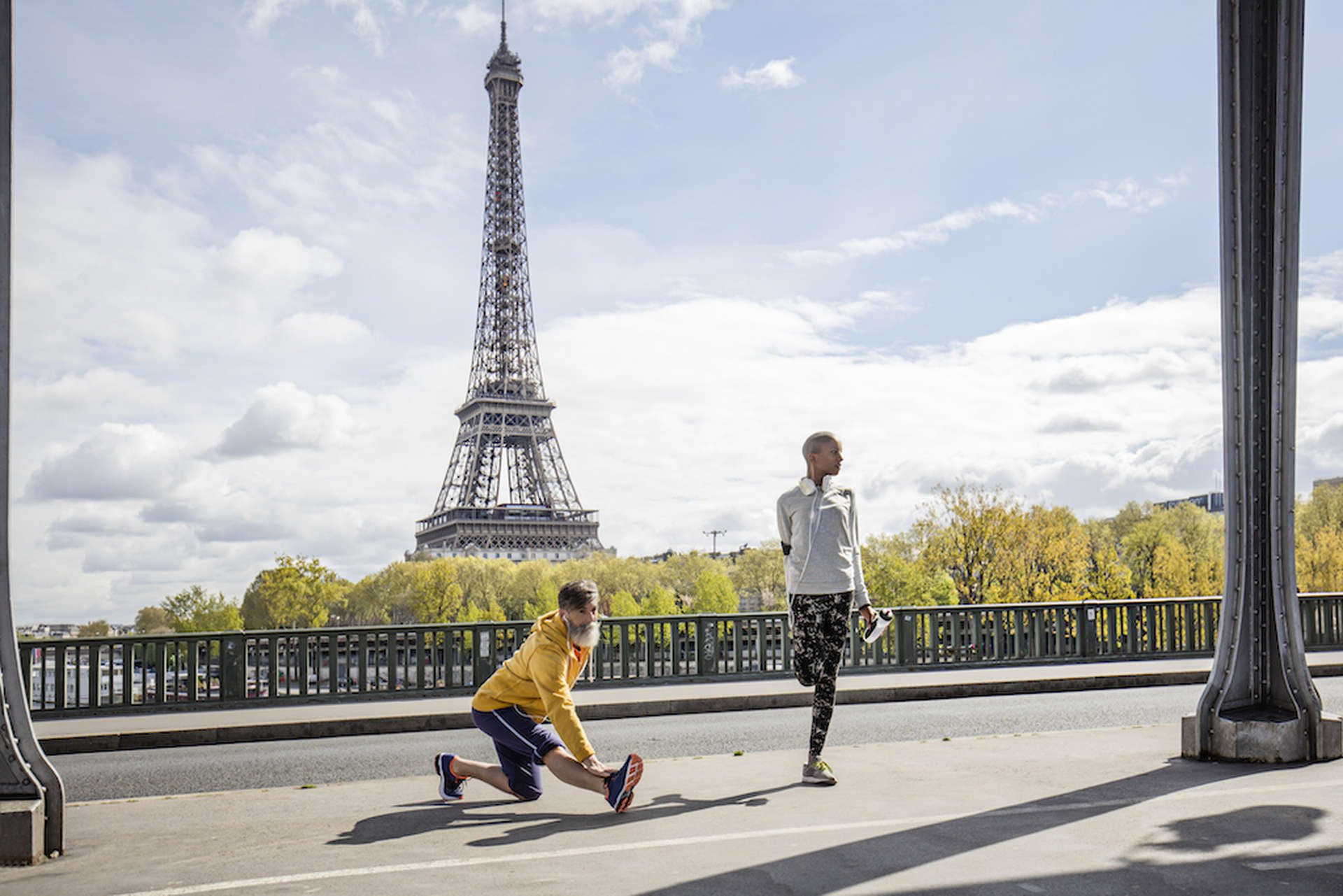 2 uomini fanno stretching davanti alla Torre Eiffel, Parigi.