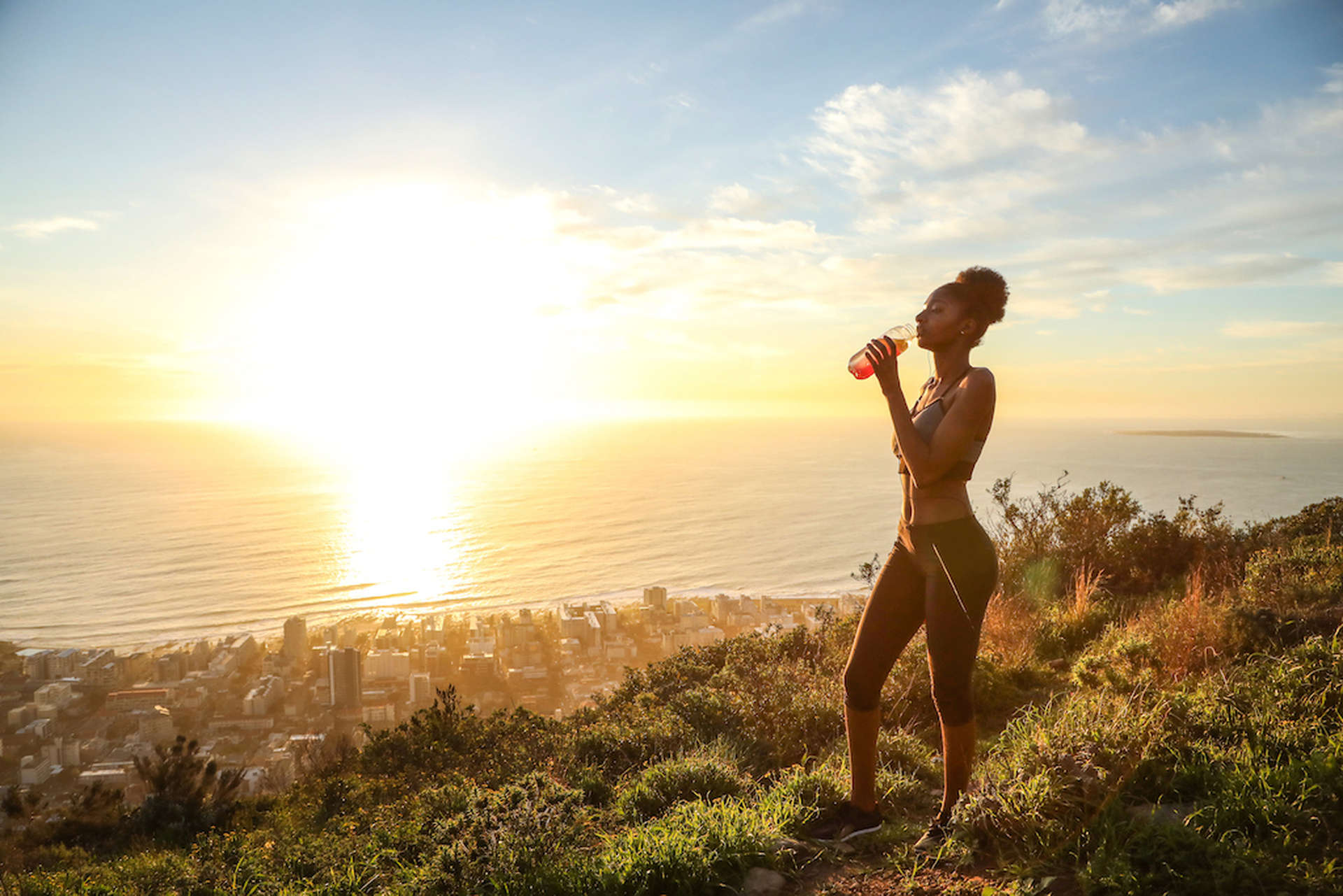 Femme faisant du jogging le long d'un sentier au sommet d'une colline surplombant la mer