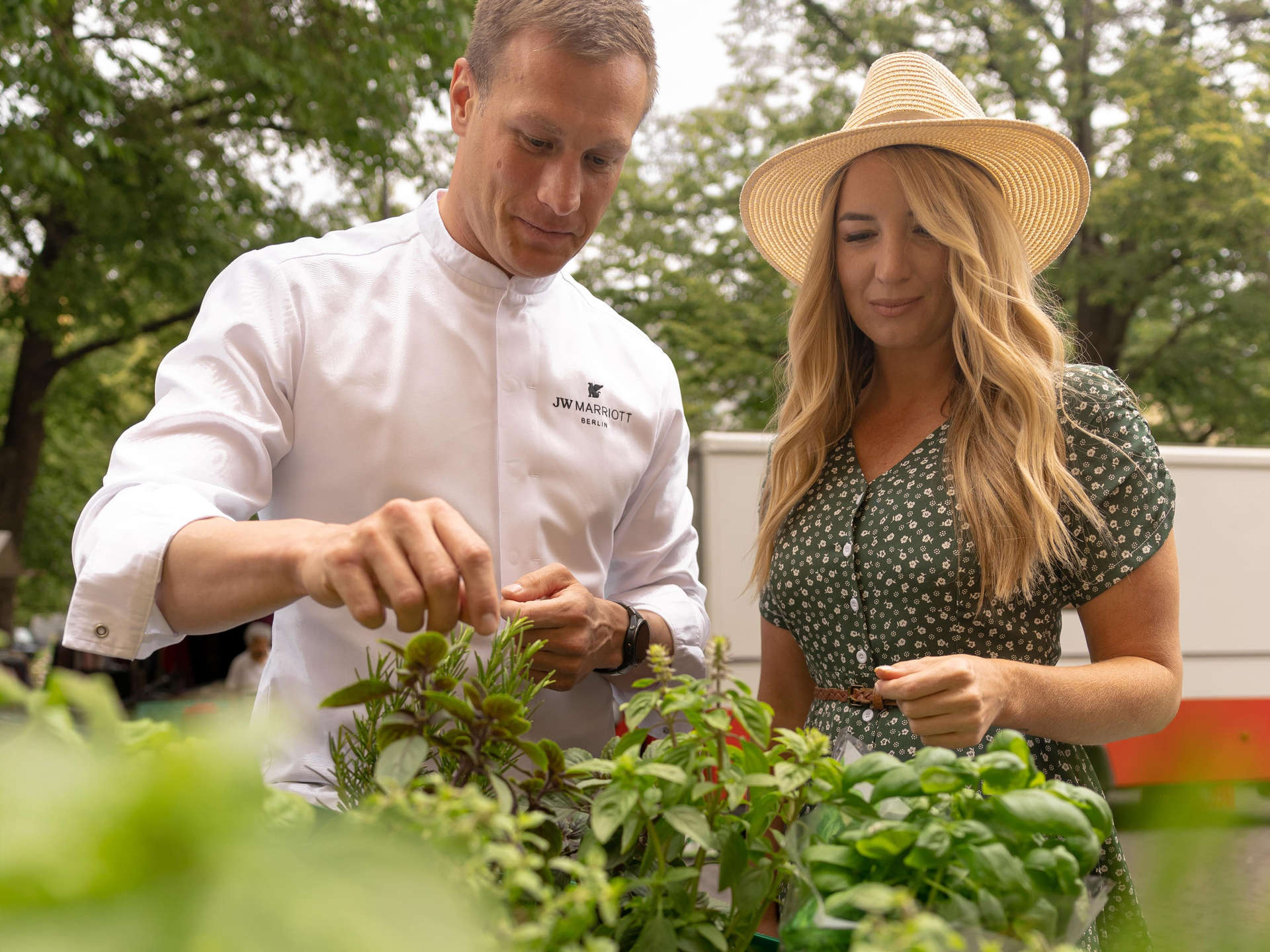 JW Marriott Berlin’s Executive Chef Friedemann Heinrich showing woman herbs.