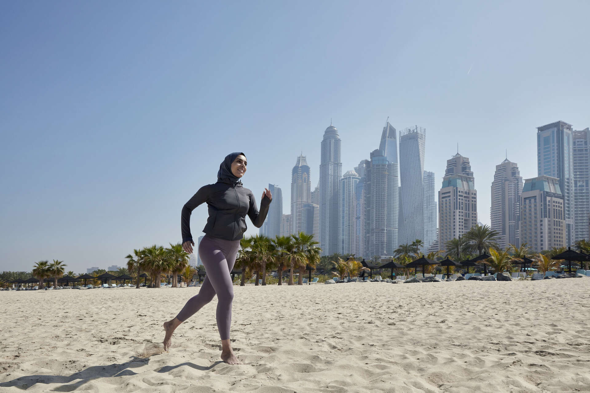 Eine Frau läuft am Strand von Abu Dhabi