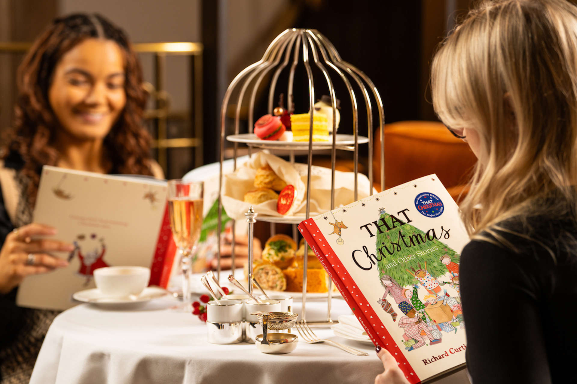 Two friends enjoying afternoon tea while reading a That Christmas picture book.