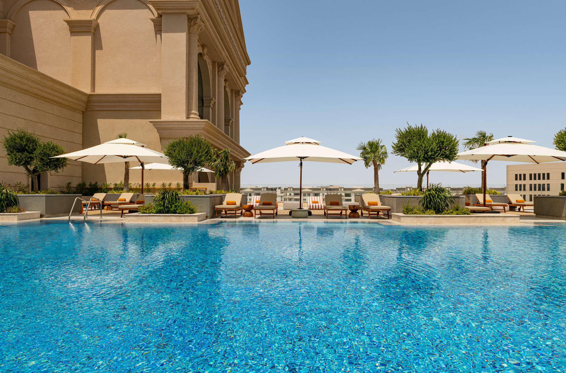 حوض السباحة الخارجي المظلل بأشجار النخيل في فندق لو رويال ميريديان الدوحة