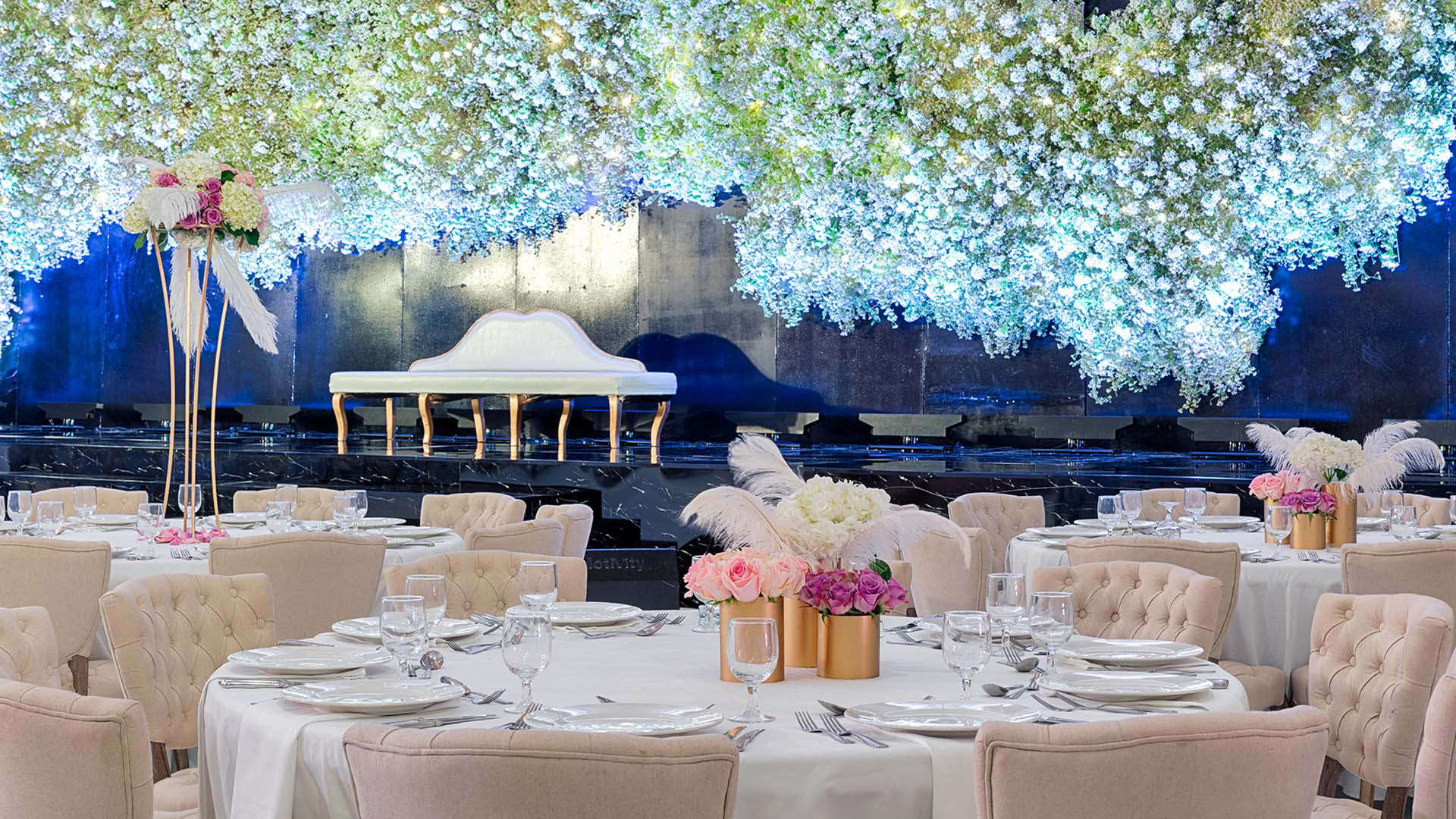 Une table de mariage avec des fleurs et un imposant lustre en verre à Abu Dhabi.