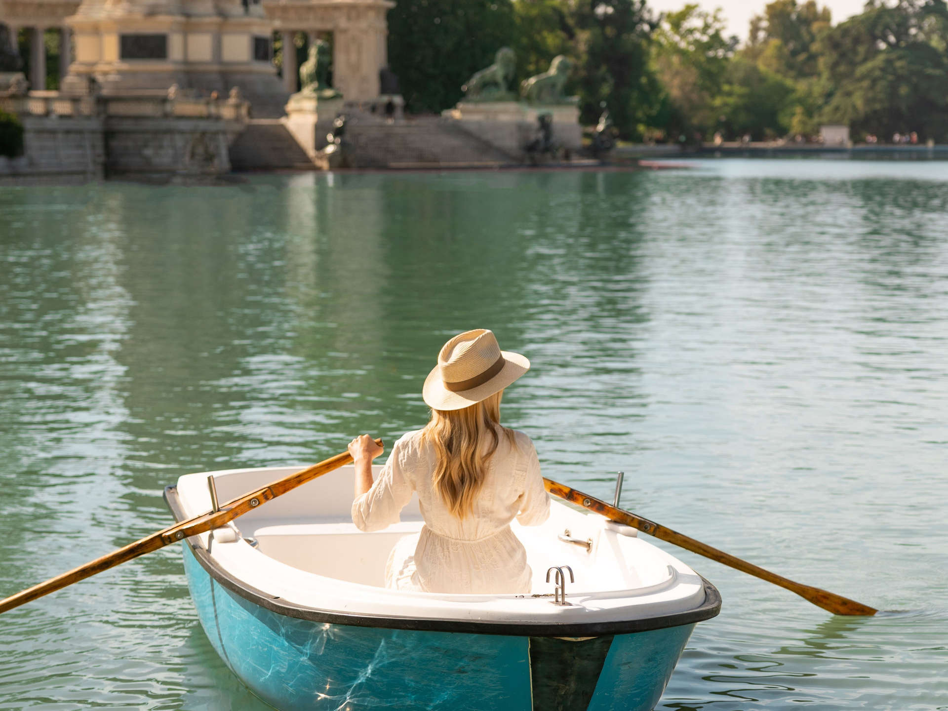 Woman rows a boat on the lake at El Retiro, Madrid.