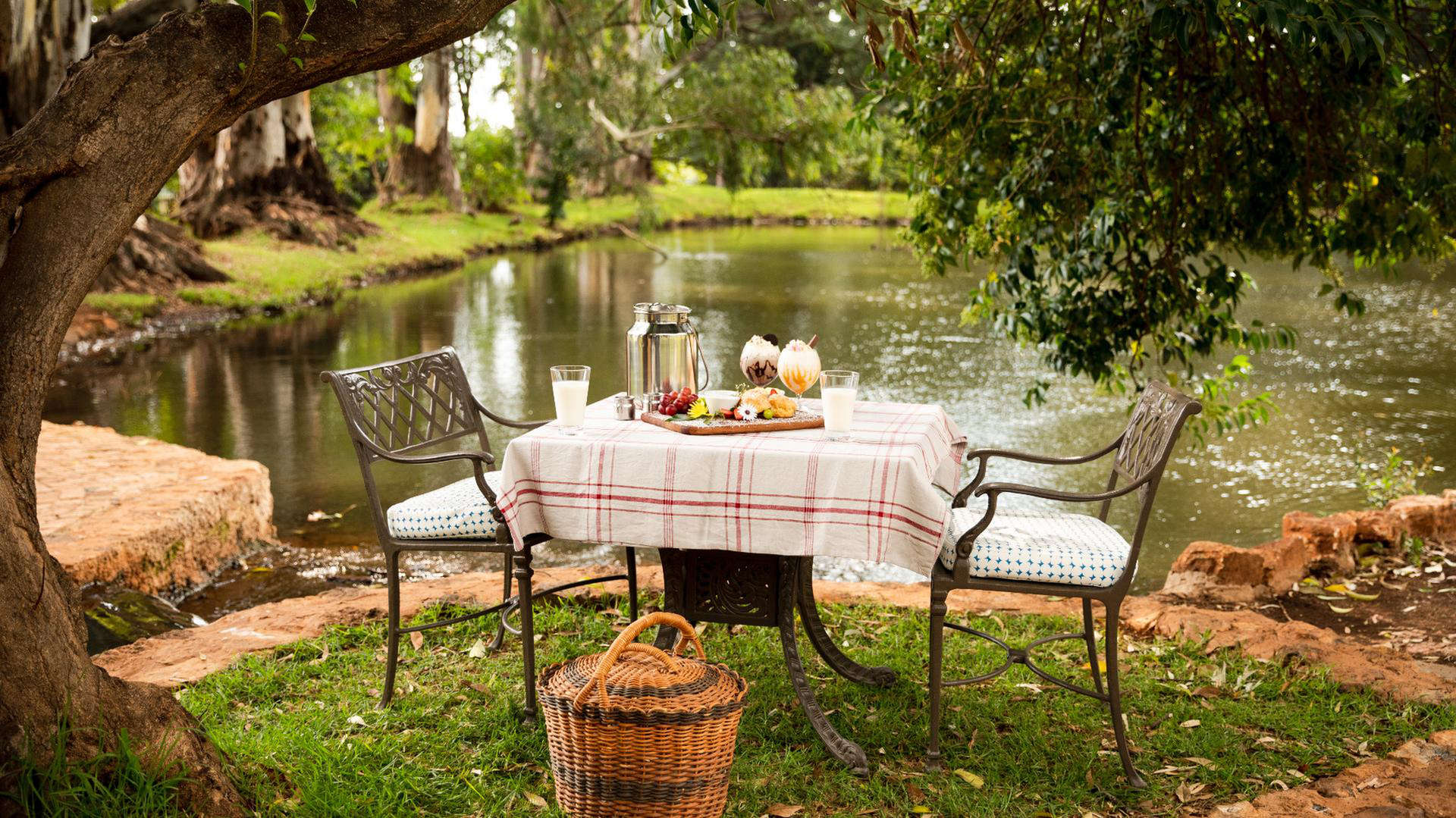 table by water with meal and picnic basket